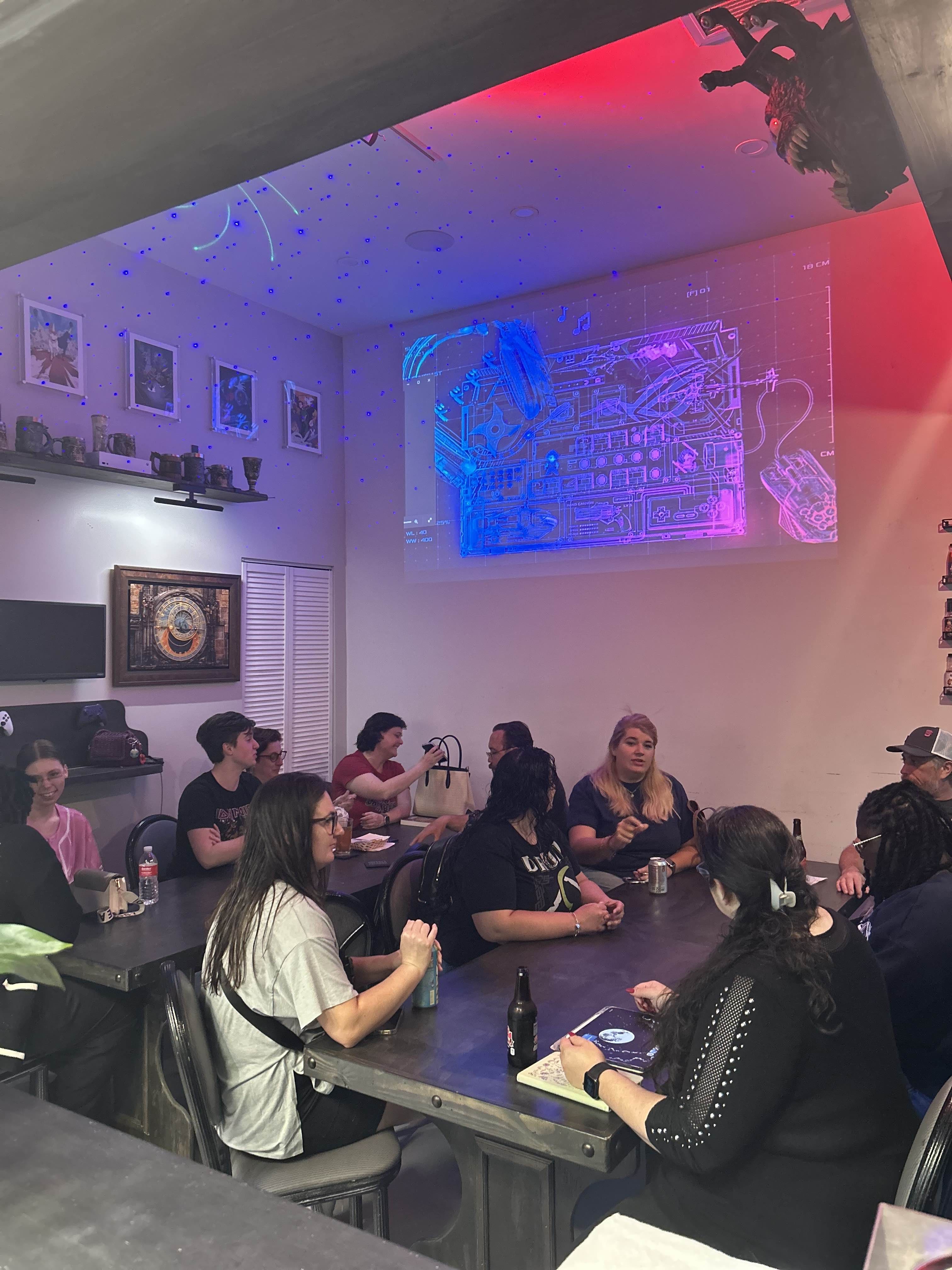 Skillshotz Gaming book club members gathered under blue ambient lighting with projector display in Deerfield Beach